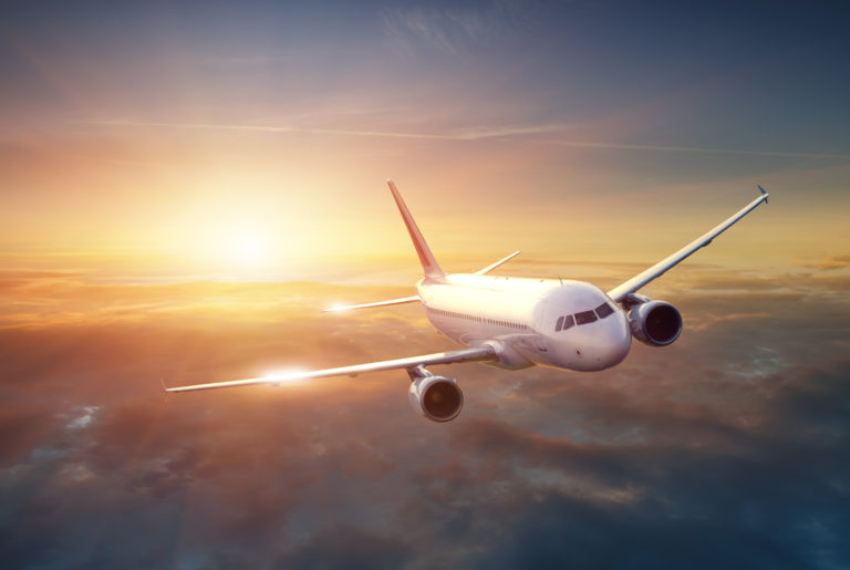 Air plane flying in front of a sunset