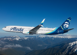 Alaska Airlines plane flying with mountains in the background