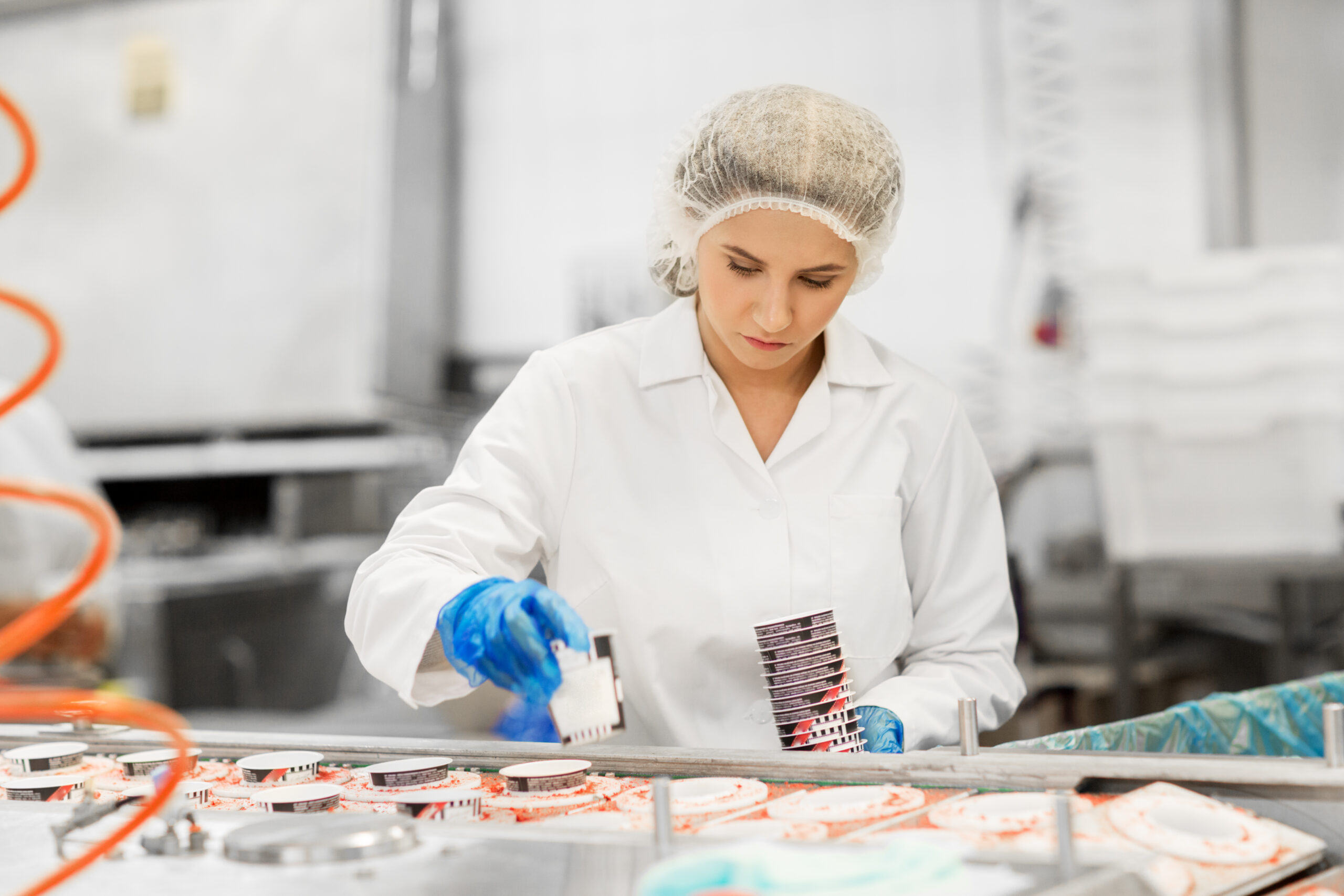 A woman in a white-coat and blue gloves in a factory