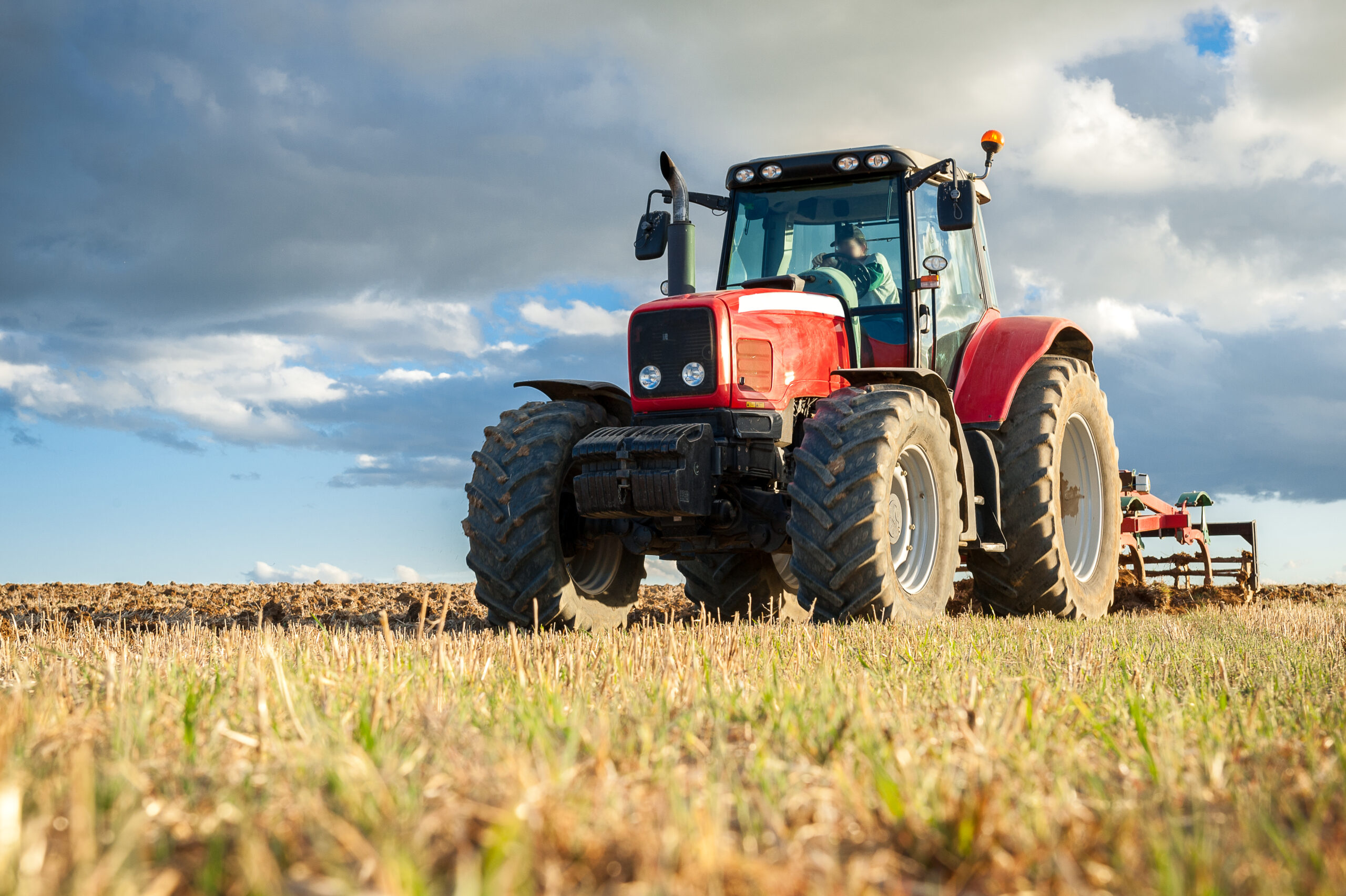 Agricultural machinery in the foreground carrying out work in the field